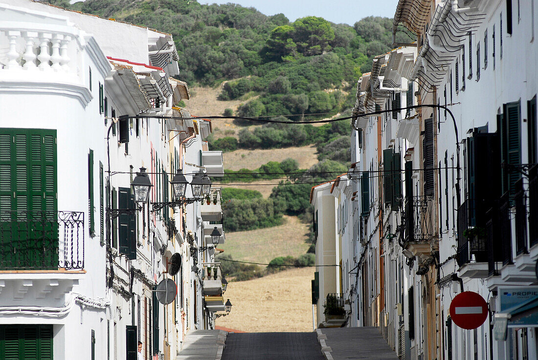 Street with houses in Es Mercadal leading towards a hill, Minorca, Balearic Islands, Spain