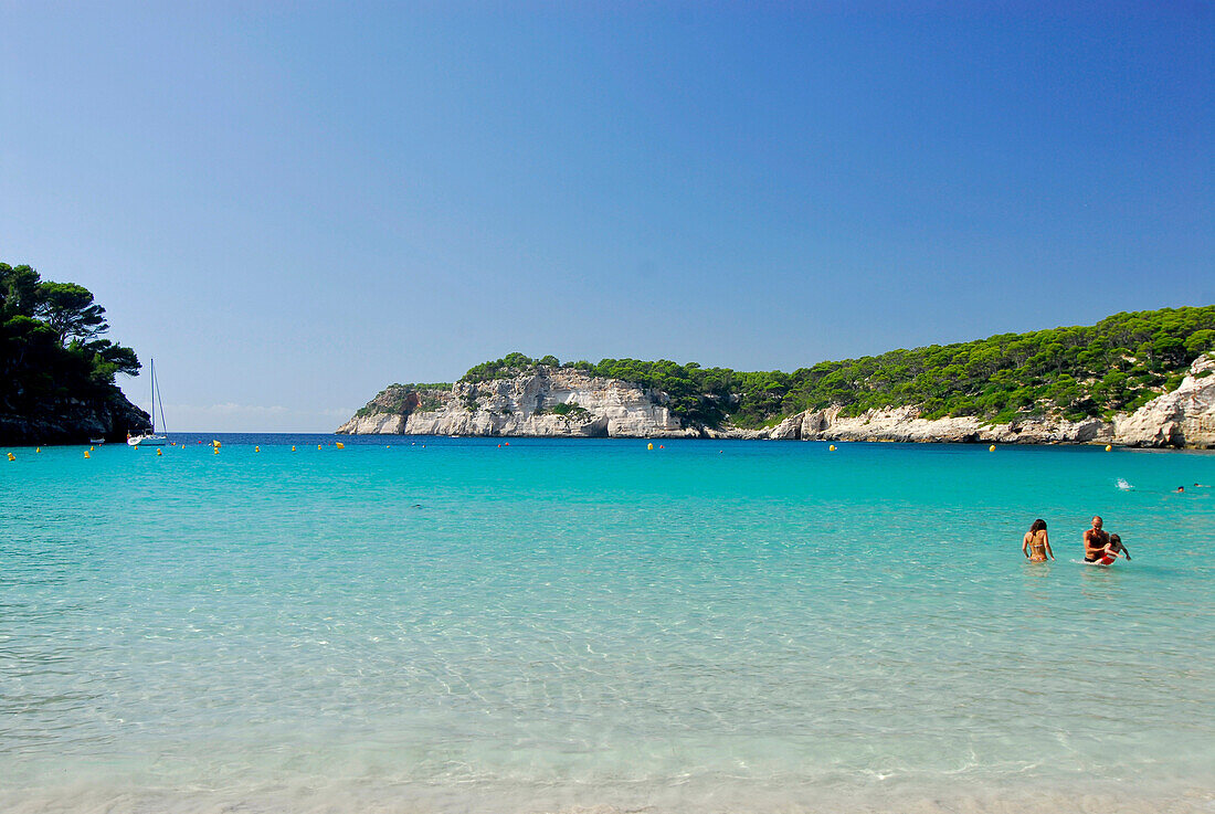 Leute beim Baden im Meer, Sandstrand am türkisfarbenen Wasser der Cala Galdana, Menorca, Balearen, Spanien