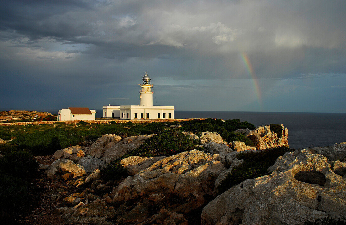 Leuchtturm mit Regenbogen und Wolken am Cap de Cavallaria, Menorca, Balearen, Spanien