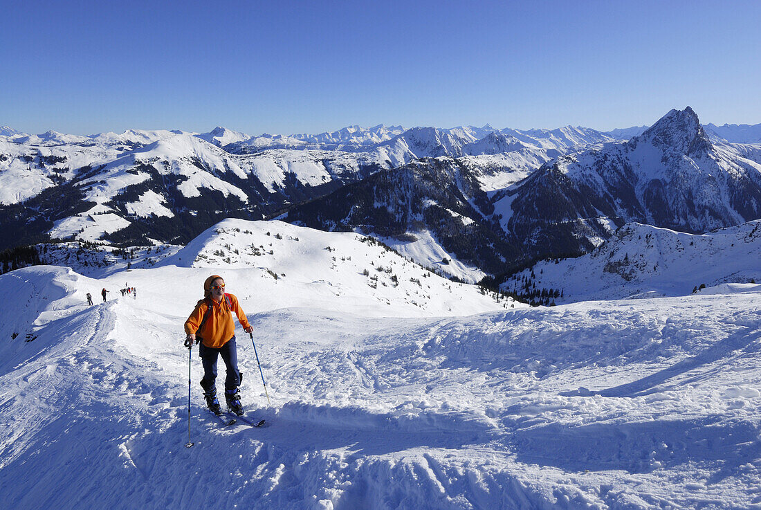 Woman backcountry skiing ascending snow ridge, Kitzbuehel range, Tyrol, Austria