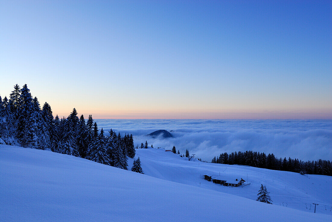Verschneite Almhütte mit Nebelmeer in der Abenddämmerung, Kampenwand, Chiemgauer Alpen, Chiemgau, Bayern, Deutschland