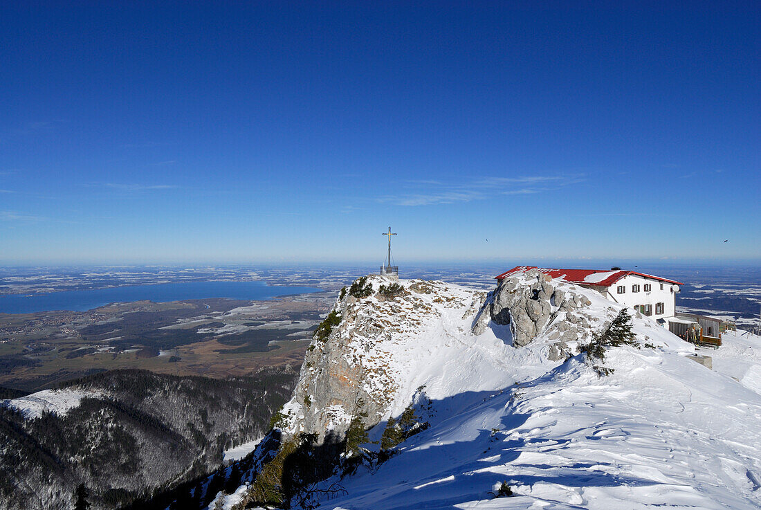 Gipfelkreuz und Hochfellnhaus mit Chiemsee im Hintergrund, Hochfelln, Chiemgauer Alpen, Chiemgau, Bayern, Deutschland