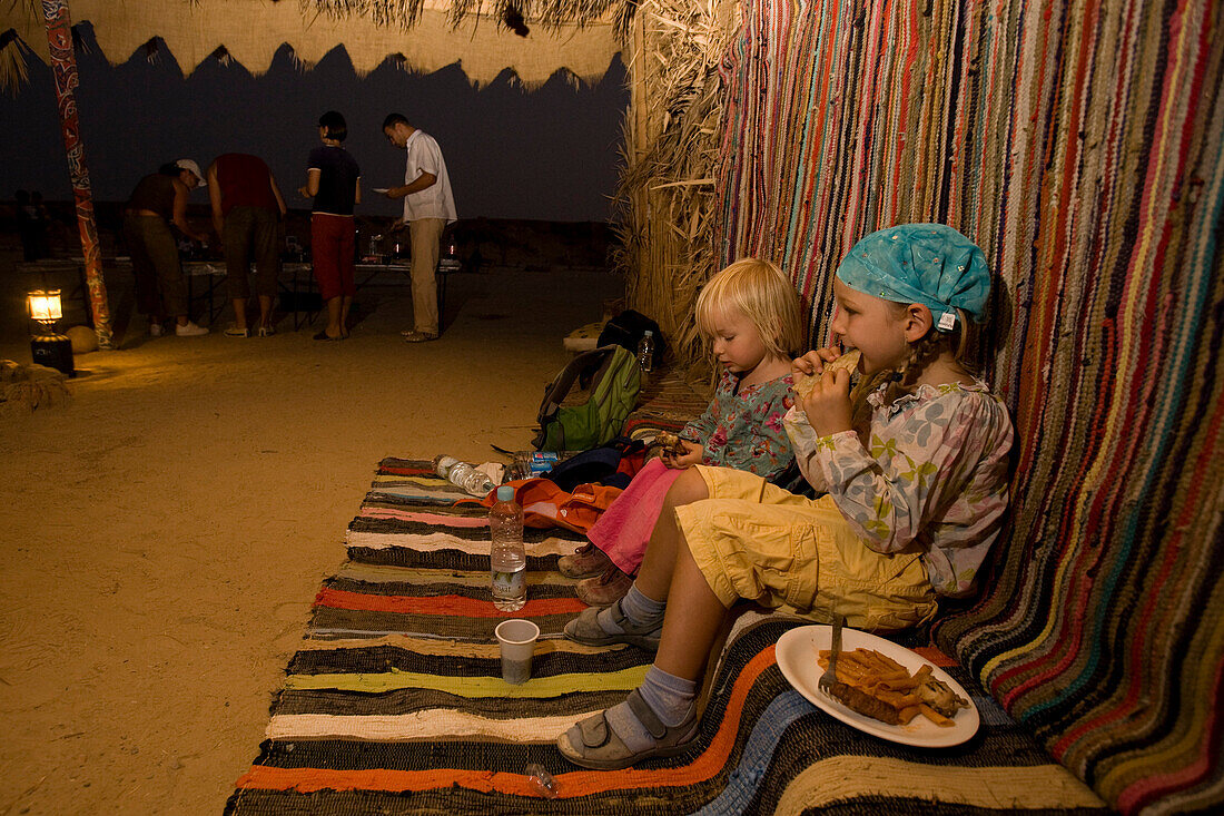 Two children, girls, 5 and 3, eating inside a bedouin tent, Marsa Alam desert, Red Sea, Egypt