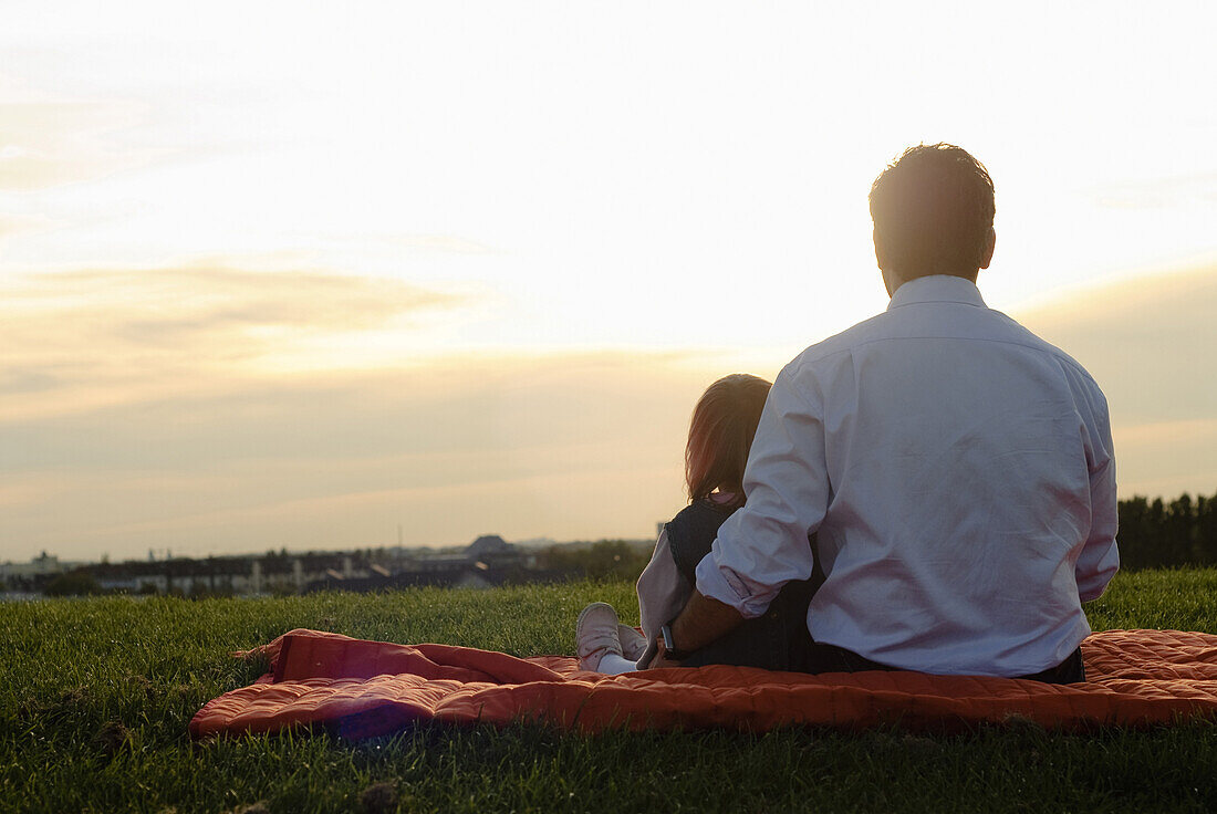 Vater und Tochter beobachten Sonnenuntergang, Englischer Garten, München, Bayern, Deutschland