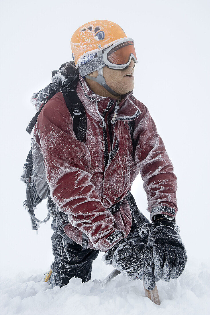 Mountaineer climbing snow covered mountain in whiteout