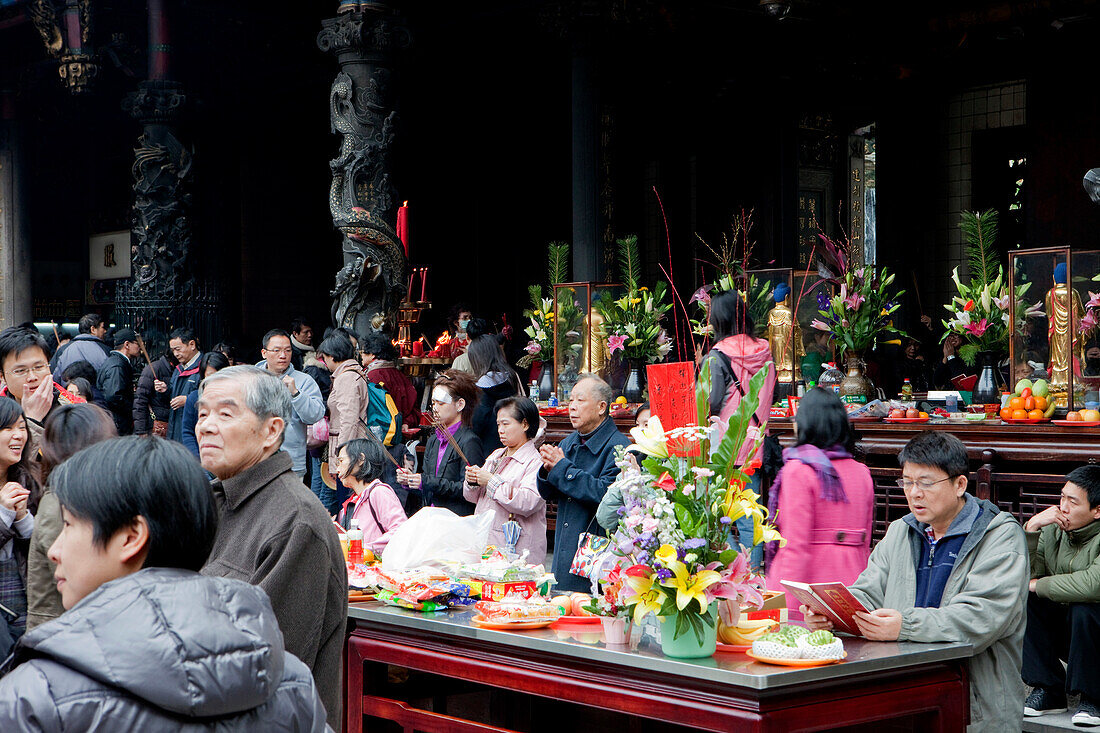 Opfergaben und betende Buddhisten im Innenhof des Longshan Tempels, Taipeh, Taiwan, Asien