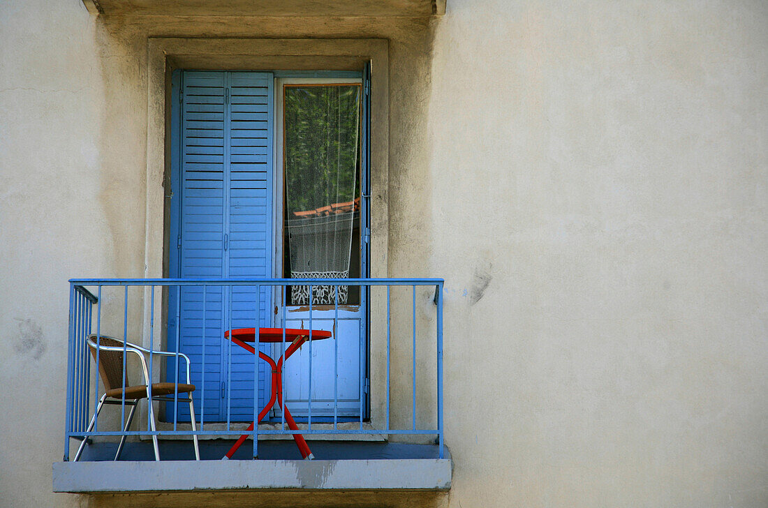 Balcony with table and chair on it and a curtain in the window, Arles, France, Europe