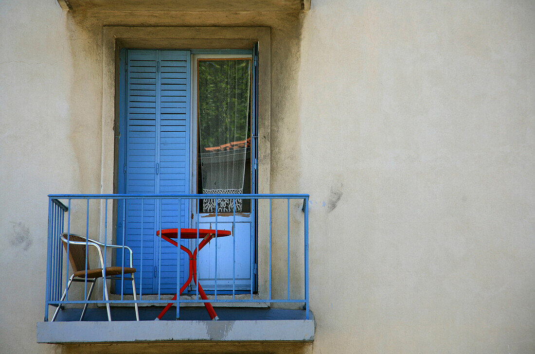 Balkon mit Tisch und Stuhl und Vorhang im Fenster, Arles, Frankreich, Europa