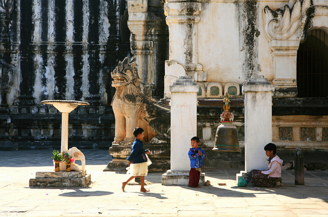 Children playing inside the sunlit Manuha Temple, Bagan, Myanmar, Burma, Asia
