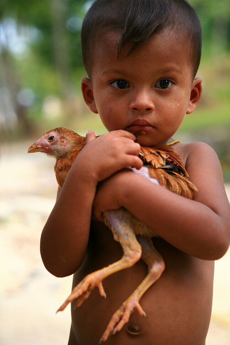 Sea gypsy, Moken boy carrying a chicken, Mergui Archipelago, Andaman Sea, Myanmar, Burma, Asia