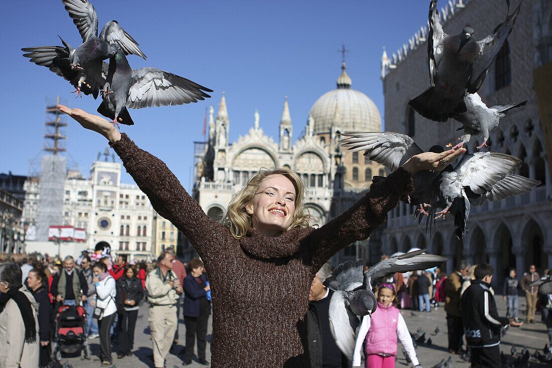 29 year old woman with pigeons in St Marks Square, Venice. Veneto, Italy