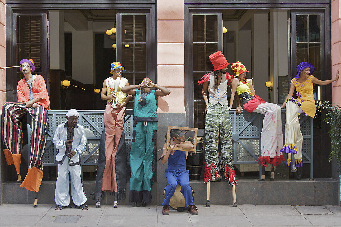 A group of street performers on stilts taking a break.