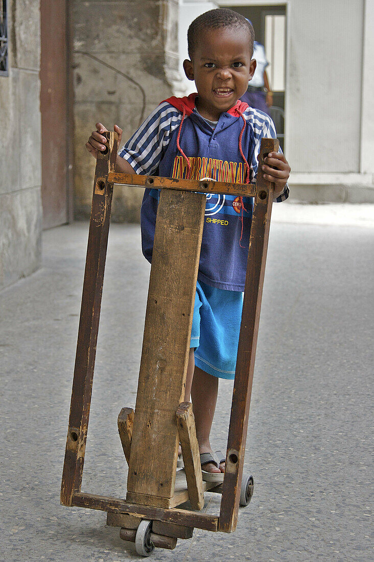 A young boy with a home made wooden scooter