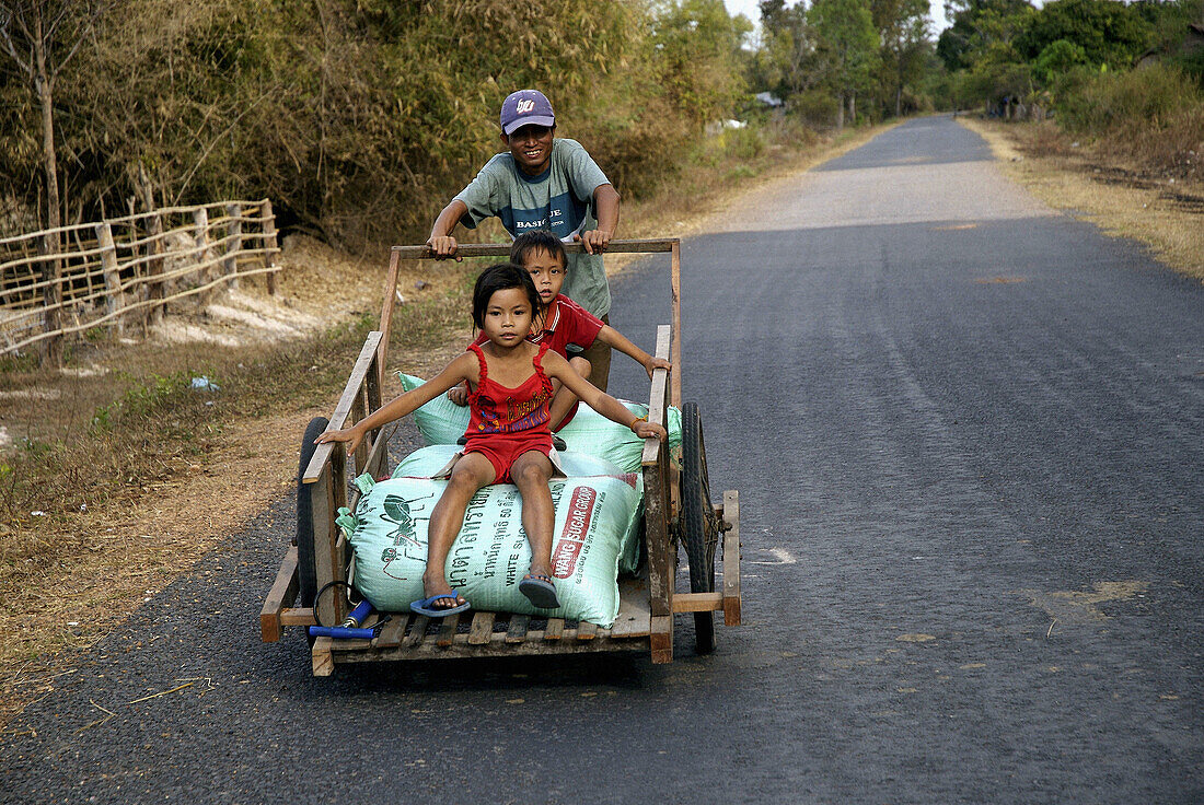 Lao farmer with a handbarrow and his kids, Laos