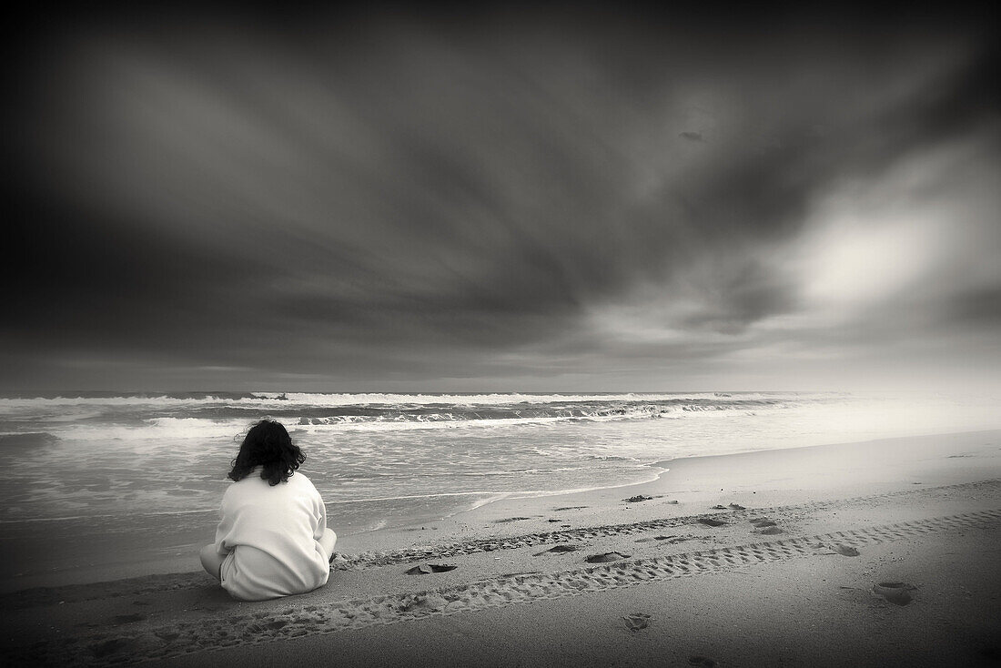 Joven adolescente sentado en la playa.