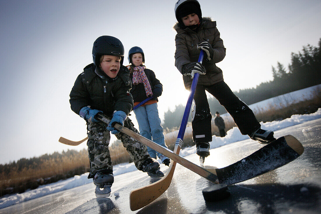 Children playing hockey on lake Buchsee, Munsing, Upper Bavaria, Germany