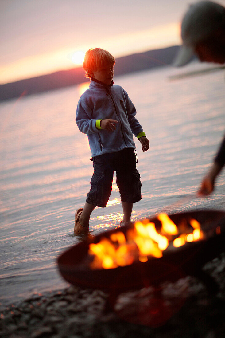 Junge bei einem Lagerfeuer am Starnberger See, Bayern, Deutschland