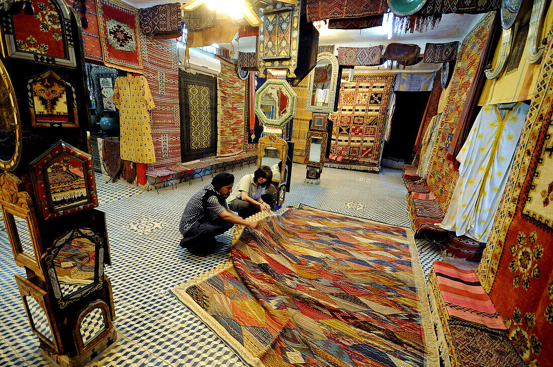 People cowering in front of a carpet at a shop at Zagora, Draa valley, South Morocco, Morocco, Africa