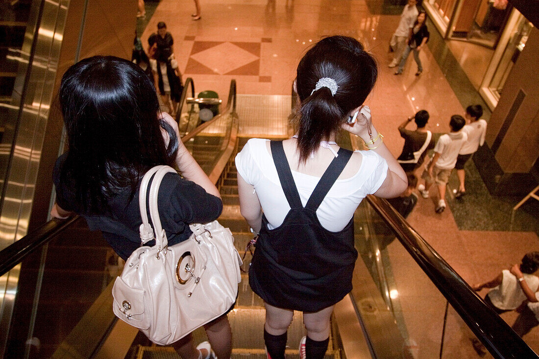 Asiatische Maedchen auf Rolltreppe im Ngee Ann City, Takashimaya shopping center, Orchard Road, Einkaufszentrum,  Singapur Asien