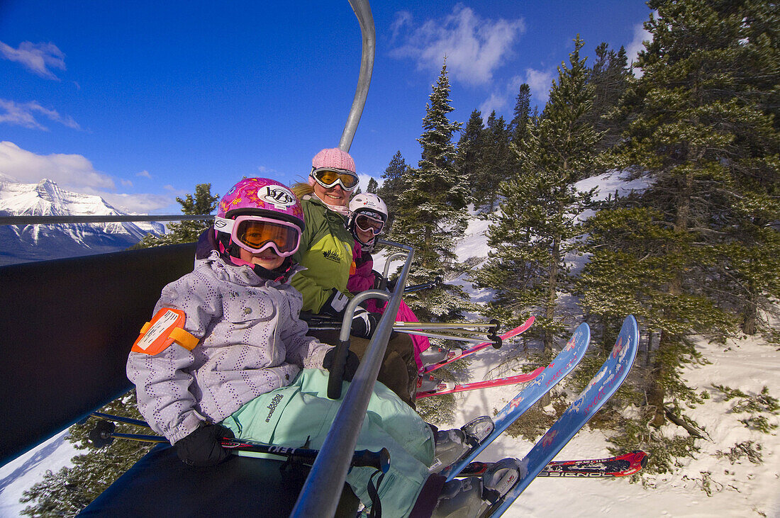 Children and their mother ride the chairlift at Lake Louise Mountain Resort, Lake Louise, Banff National Park, Alberta, Canada