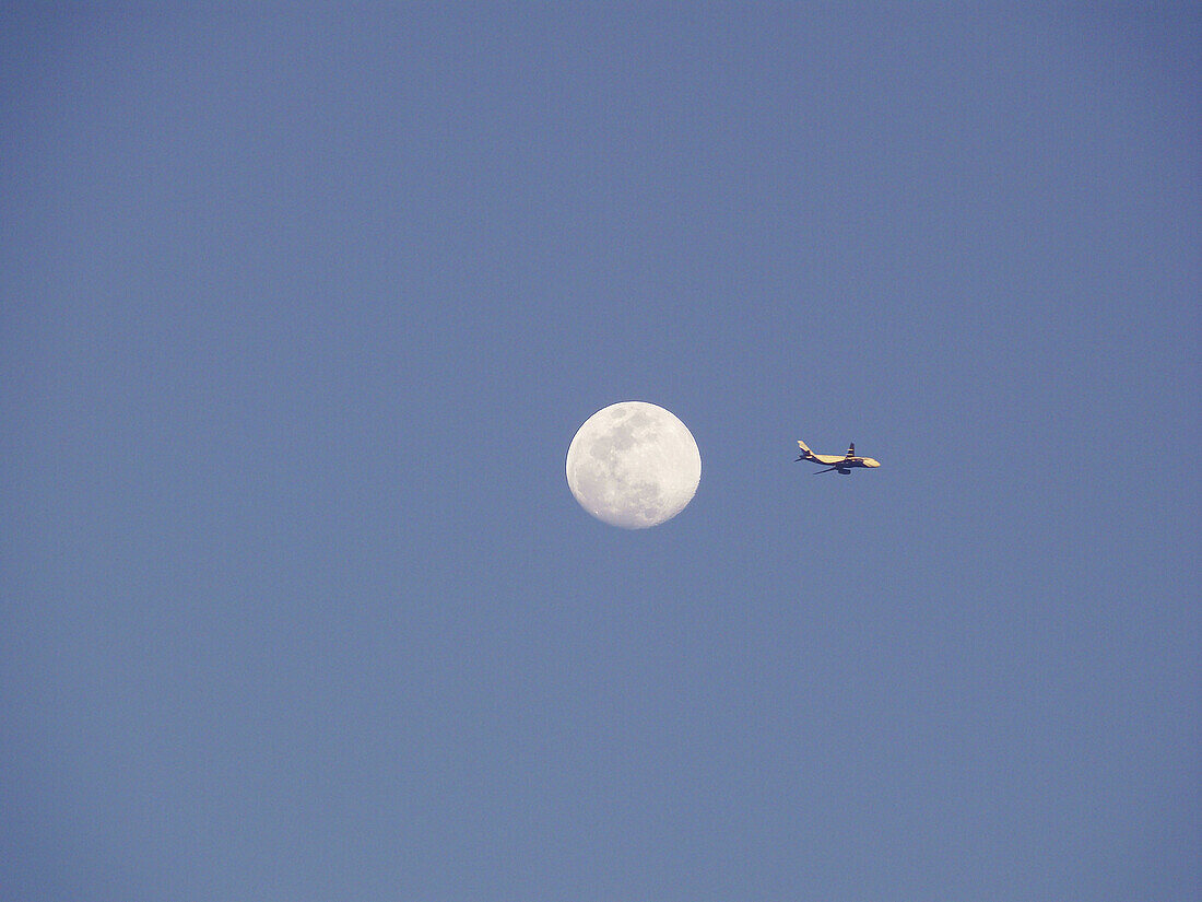 Passenger jet and moon in blue sky, low angle view  Pune, Maharashtra, India