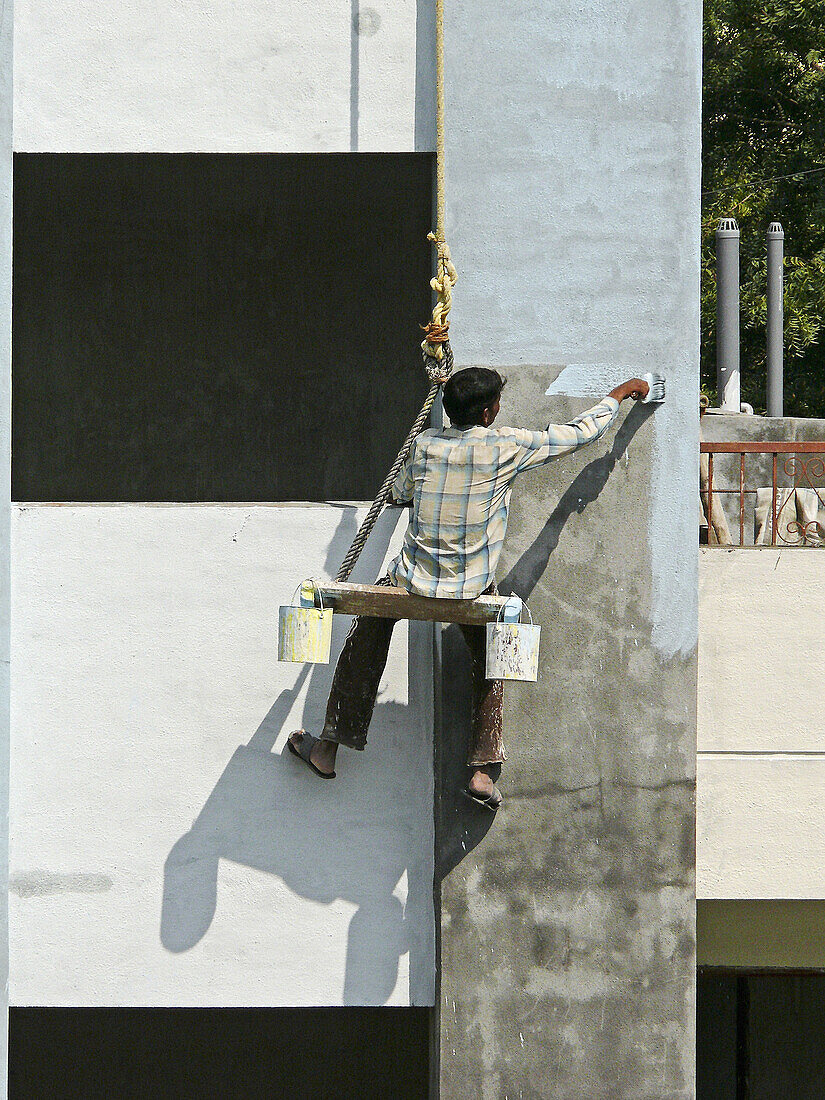 Painters are seating on cradles and working on a buildings exterior painting work  Pune, Maharashtra, India