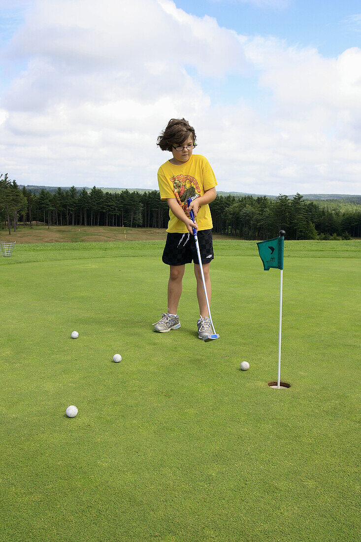 a 7 year old girl golfing at putting green