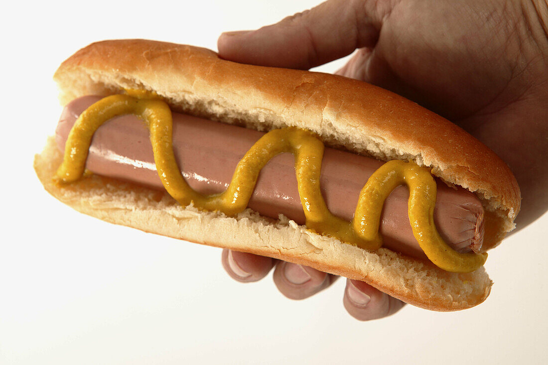 Hot Dog mit Senf in einer Hand