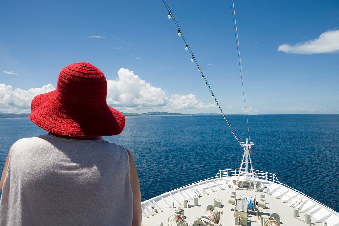 Frau mit rotem Hut und Bug der MS Columbus im Sonnenlicht, Mamanuca Inselgruppe, Fidschi Inseln, Südsee, Ozeanien
