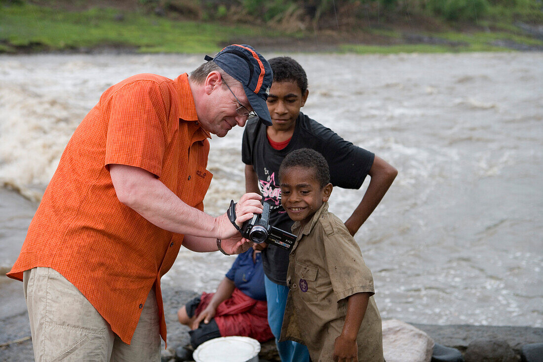 Tourist showing pictures on his video camera to fijian boys, Navala, Viti Levu, Fiji Islands, South Pacific, Oceania