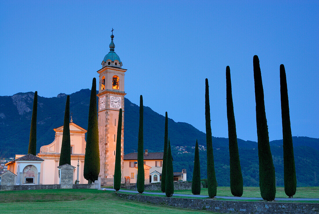 Illuminated church San Abbondino near Gentilino with cypress alley, Gentilino, Lugano, Ticino, Switzerland