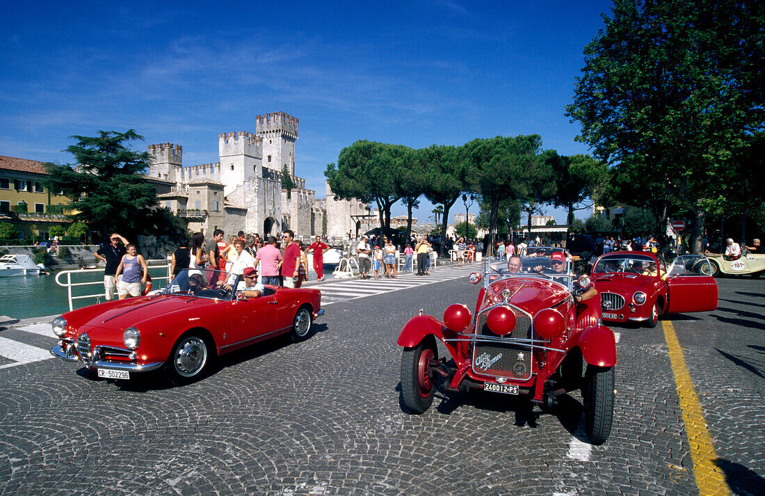 Classic car show in front of the Scaliger castle under blue sky, Sirmione, Lake Garda, Lombardy, Italy, Europe