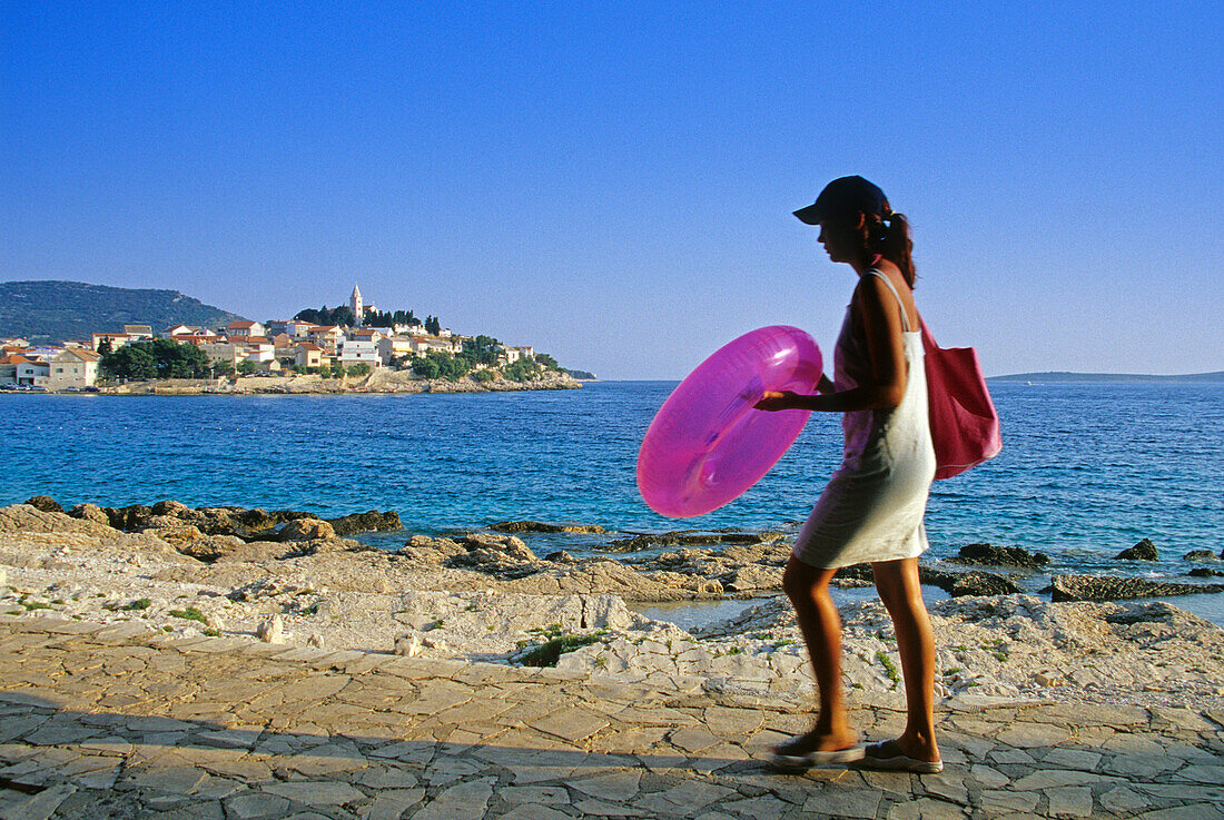 Eine Frau auf der Strandpromenade von Primosten, Kroatische Adriaküste, Dalmatien, Kroatien, Europa