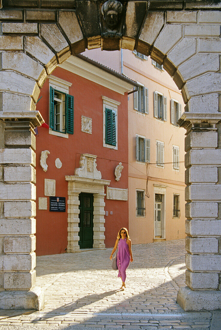 Eine Frau und venezianisches Balbi Tor in der Altstadt von Rovinj, Kroatische Adriaküste, Istrien, Kroatien, Europa