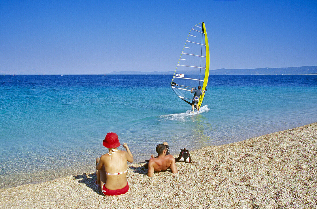 Windsurfer und Menschen am Strand im Sonnenlicht, Goldenes Horn, Insel Brac, Kroatische Adriaküste, Dalmatien, Kroatien, Europa