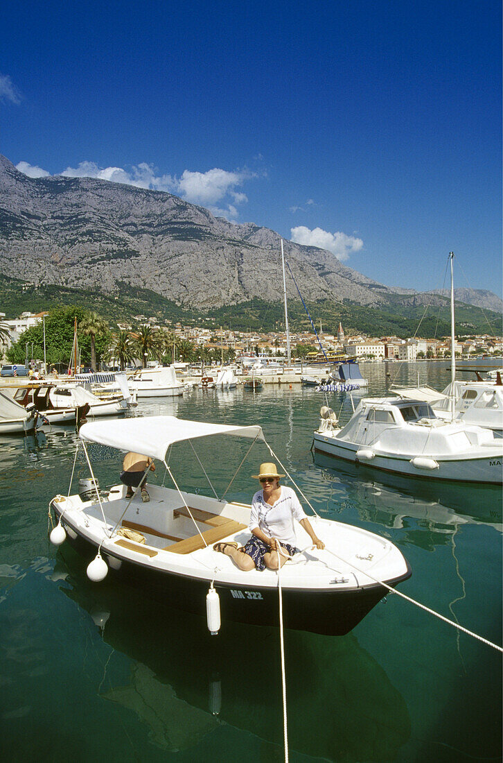 Frau auf sonnenbeschienenem Motorboot im Hafen von Makarska, Makarska Riviera, Kroatische Adriaküste, Dalmatien, Kroatien, Europa
