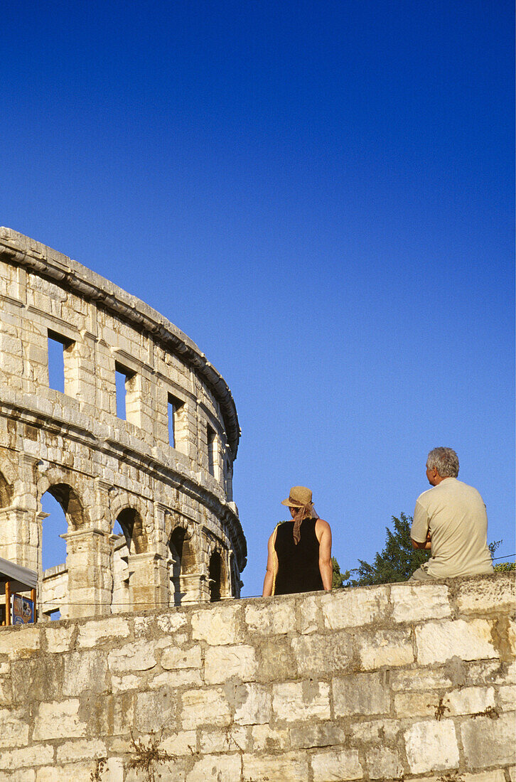 Couple on the city wall in front of the roman amphitheater in the sunlight, Pula, Croatian Adriatic Sea, Istria, Croatia, Europe