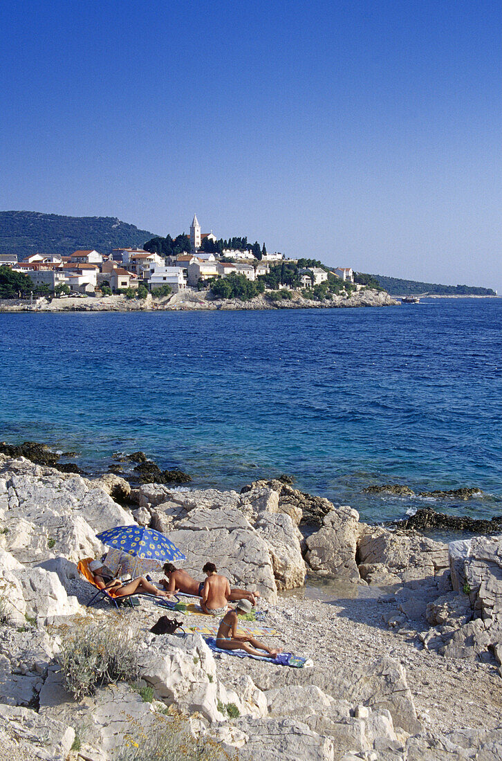 Menschen sonnen sich an der Küste vor Primosten, Kroatische Adriaküste, Dalmatien, Kroatien, Europa