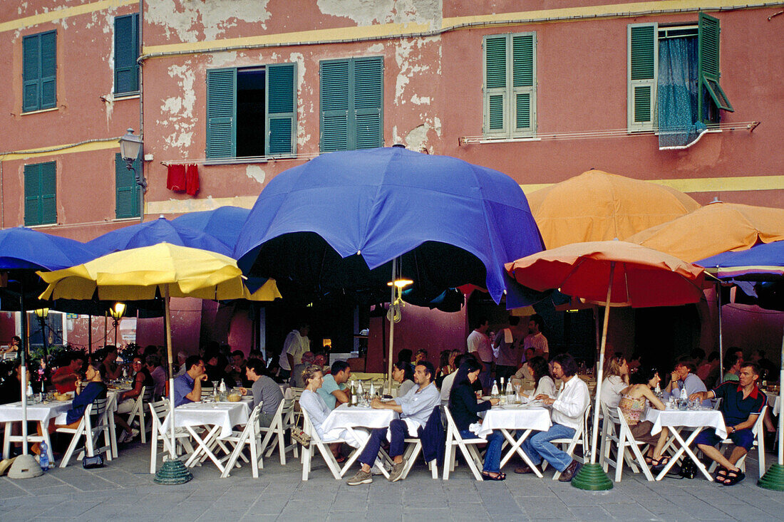 Menschen sitzen unter Sonnenschirmen vor einem Restaurant, Vernazza, Cinque Terre, Ligurien, Italienische Riviera, Italien, Europa