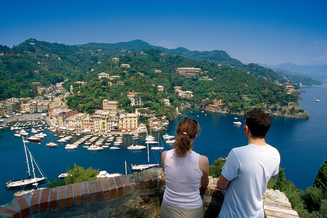 Junges Paar blickt auf den Jachthafen, Portofino, Italienische Riviera, Ligurien, Italien, Europa