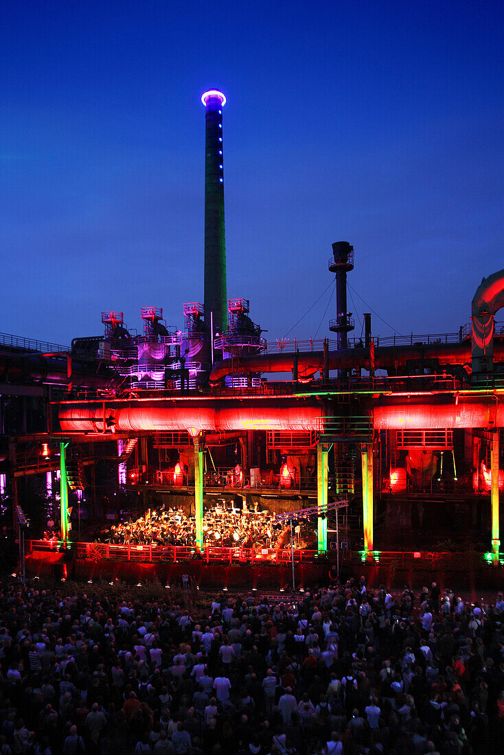 The Duisburg Philharmonic Orchestra playing in front of the illuminated backdrop of the Huette Meiderich, Duisburg, Ruhr Area, North Rhine-Westphalia, Germany, Europe