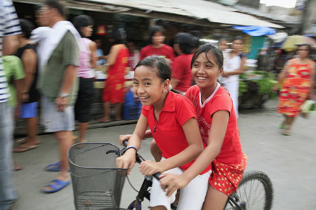 PHILIPPINES  Girls on bicycle   Scene in a street market at Bagong Silangan, Quezon City, Manila