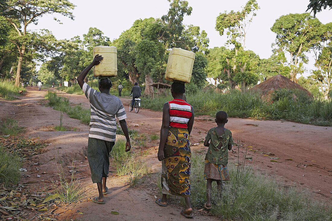 SOUTH SUDAN  Women carrying water from a hand pump well, early morning in Yei