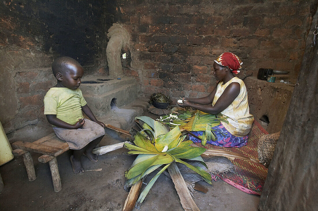 UGANDA  In the home of farmer and farmers group animator of Caritas Lugazi, Najjemba Teopista, Kasaayi village, Kayunga District  Teopista in her kitchen making the staple steamed banana dish matoke