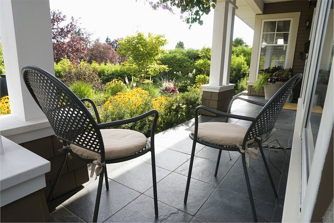 Canada, BC, Vancouver.  Metal garden chairs on porch looking out at residential garden