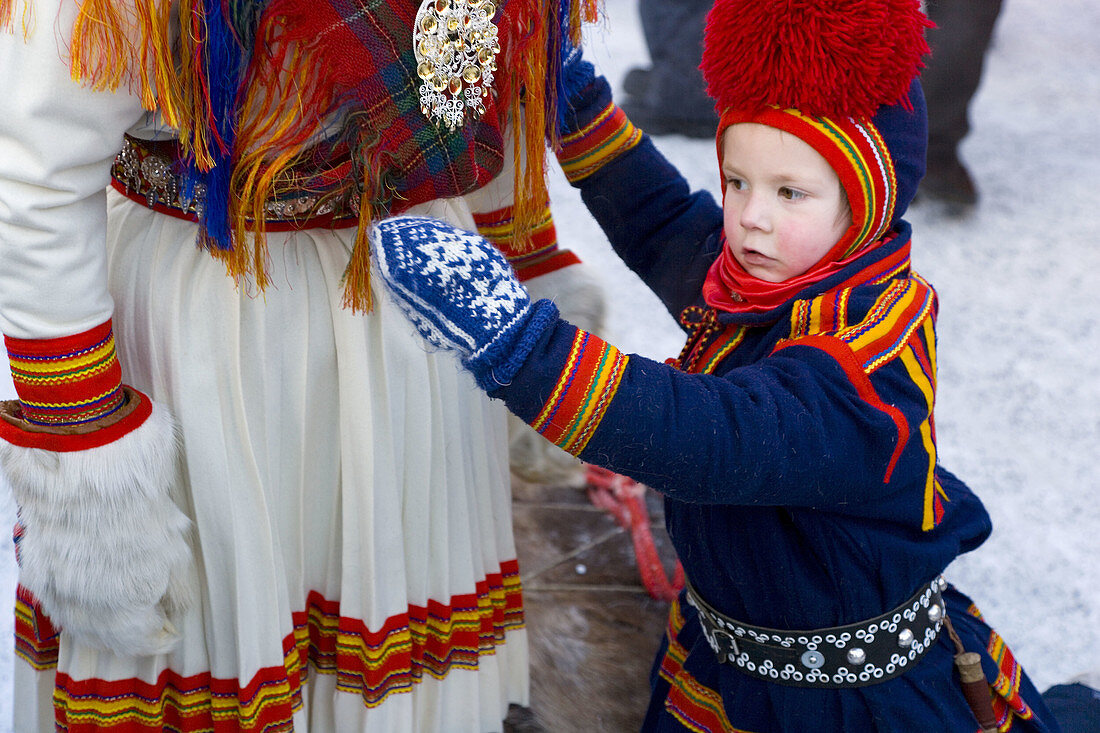 Sami (Lapp) boy with mother at winter fair. Jokkmokk, Northern Sweden
