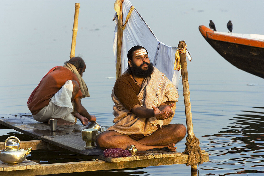 Man doing puja (Hindu devotional worship) by river Ganges at Kumba Mela festival