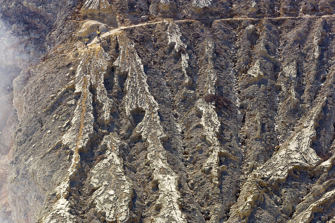 People, including man carrying sulphur on rim of volcano, Kawa Ijen, Ijen Plateau, East Java, Indonesia. People on rim of volcano including sulphur worker carrying sulphur