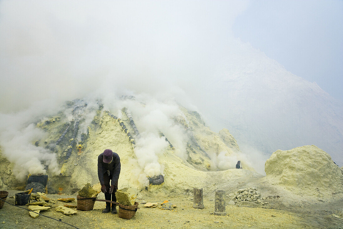 Sulphur workers, Kawa Ijen, Ijen Plateau, East Java, Indonesia. Sulphur workers collecting sulphur rocks from volcano