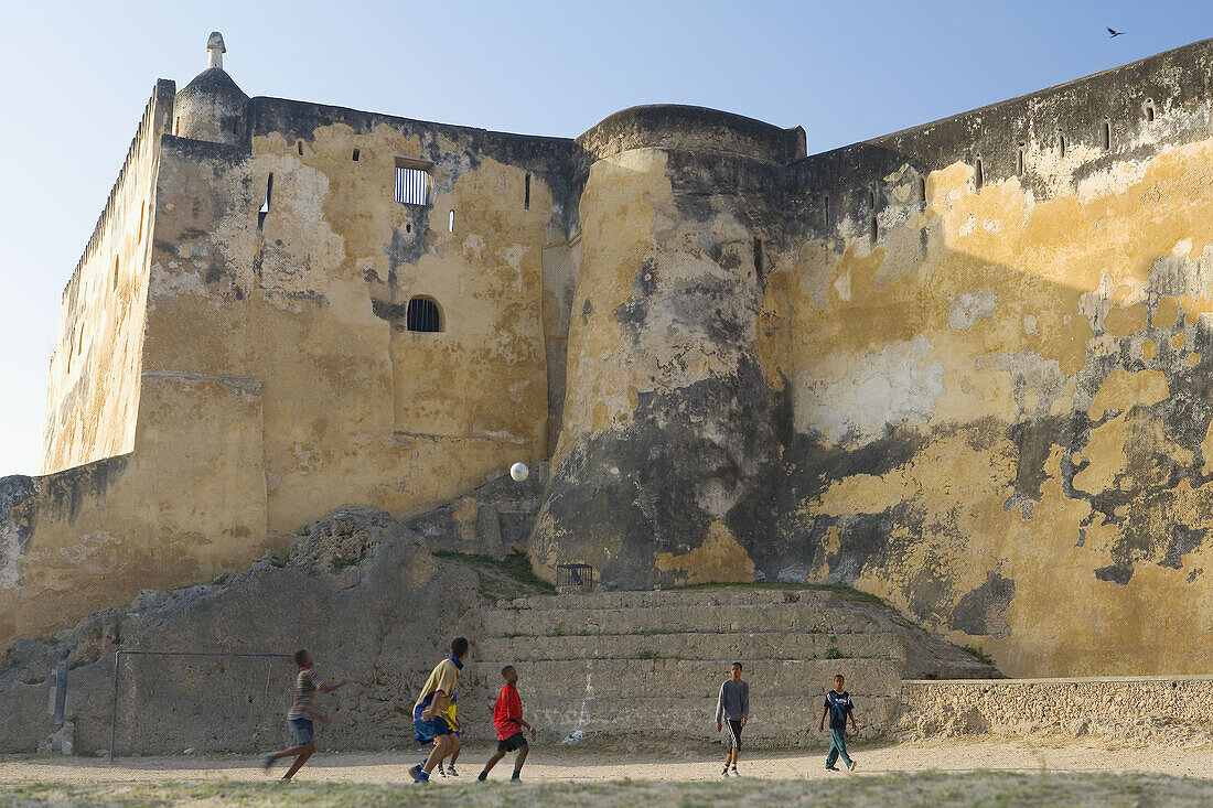 Boys playing football in front of Fort Jesus, Mombasa, Kenya